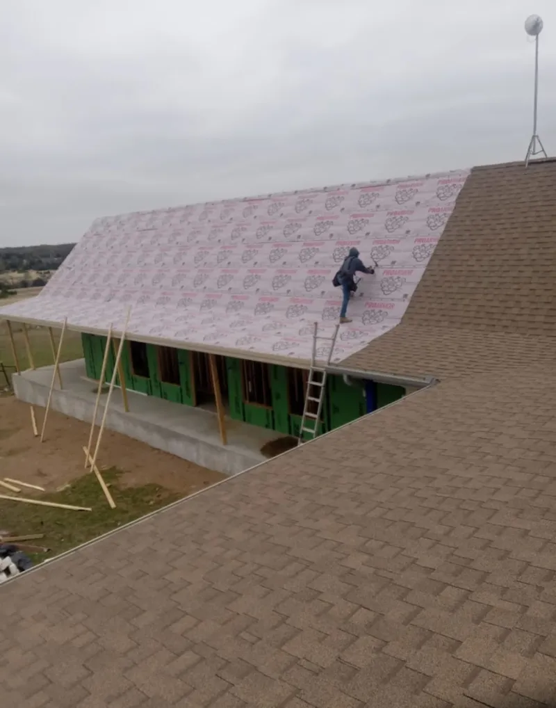 Worker preparing underlayment for a metal roof installation in Hood River